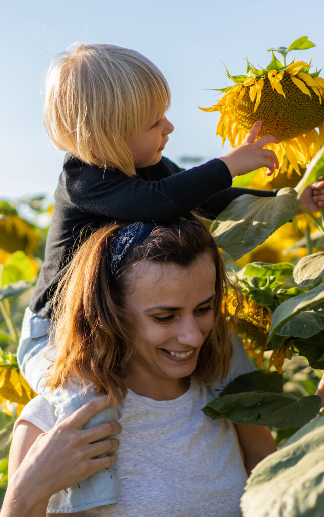 Betreuerin mit Kind im Sonnenblumenfeld