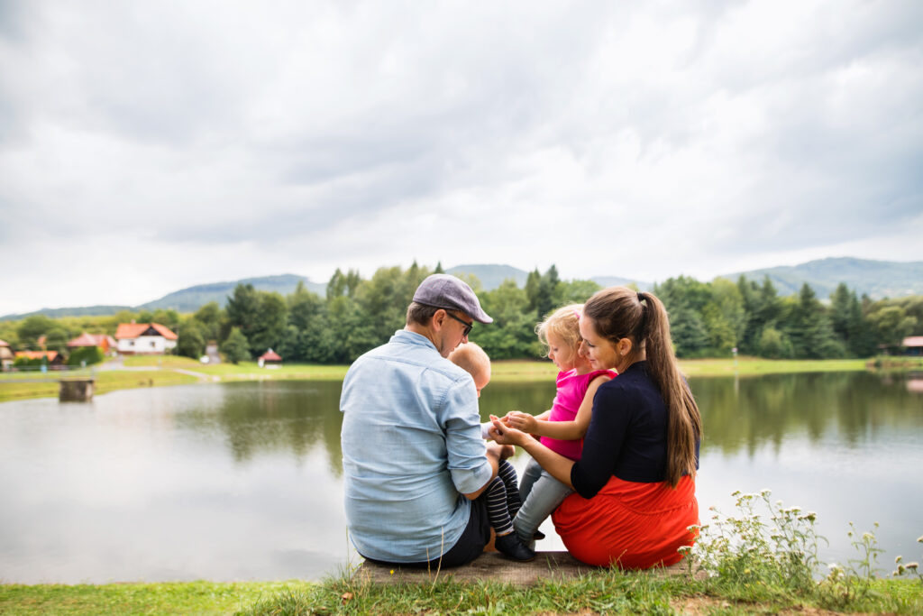 Familie sitzt zusammen am Seeufer