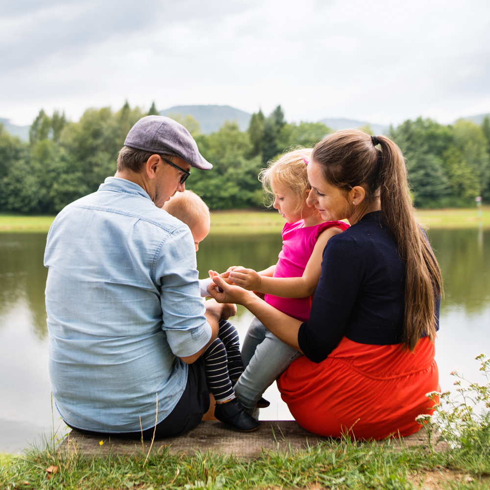 Familie sitzt zusammen am Seeufer