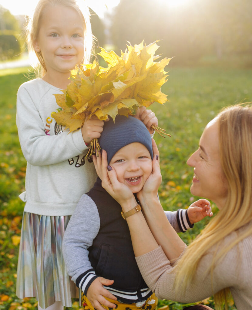 Mutter, kleiner Sohn und Tochter spielen mit Blättern