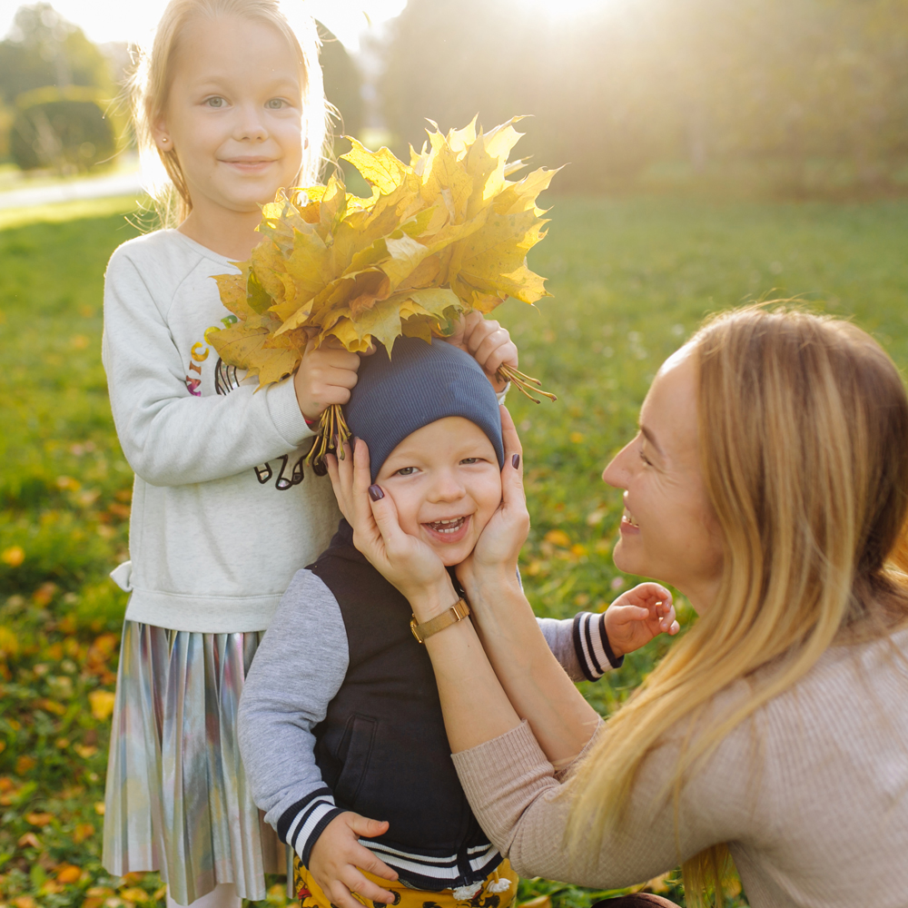 Mutter, kleiner Sohn und Tochter spielen mit Blättern